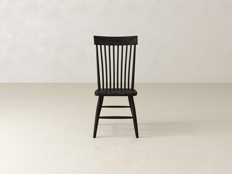 A dark wooden chair with a slatted backrest and slightly angled legs on a white background. The chairs design is simple and classic, with clean lines and a smooth finish.