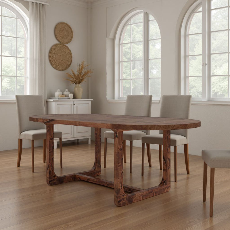 A modern dining room with the James+James Emersen Oval Dining Table in Tuscany, four upholstered chairs, light wood floors, arched windows, white walls, and a small white sideboard decorated with art and dried plants.