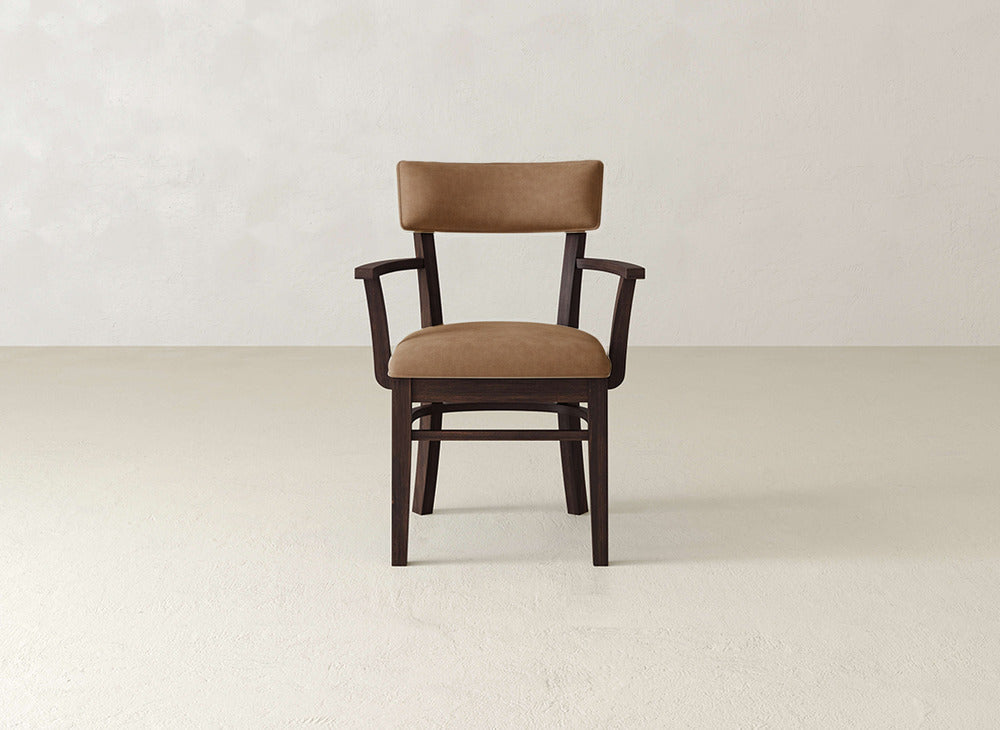 The Everly Arm Dining Chair by James+James features a modern wooden design with elegant brown cushioned seat and backrest, set against a simple, light-colored background.