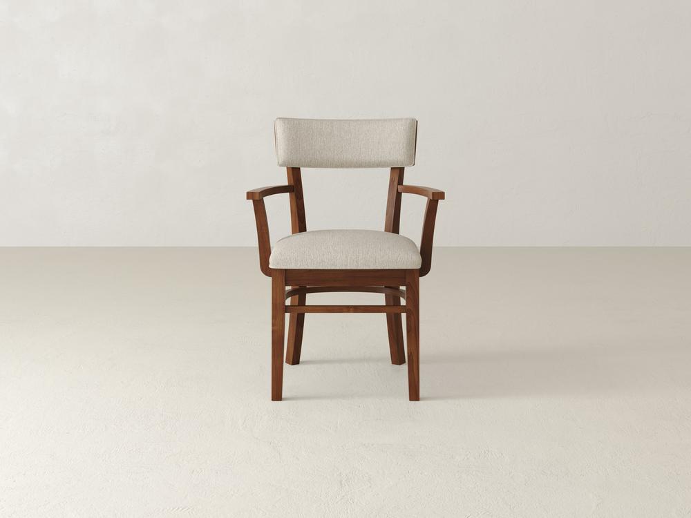 A wooden chair with light beige upholstered seat and backrest, featuring simple armrests, is placed against a plain light-colored background.