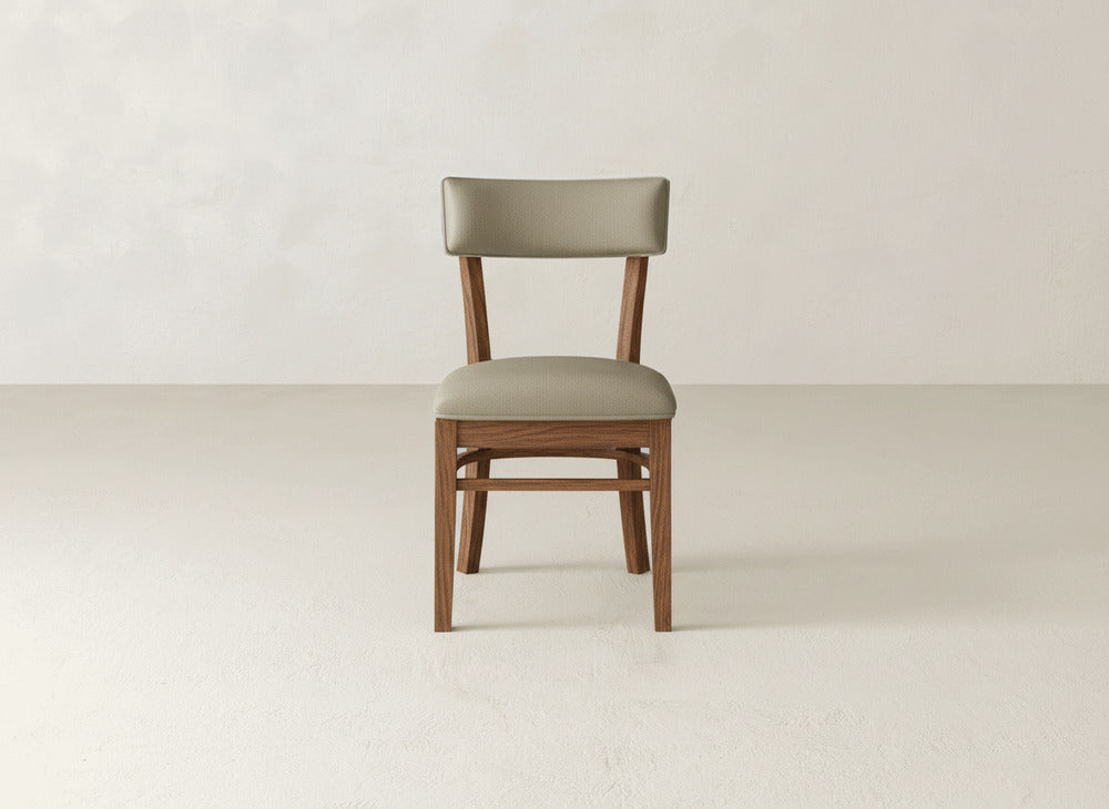The Everly Side Dining Chair by James+James features a light brown cushioned seat and backrest, displayed on a plain, light-colored floor against a neutral wall.