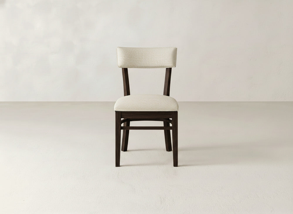 The Everly Side Dining Chair by James+James features a dark wooden frame with a light upholstered seat and backrest, shown facing forward against a plain, light background.