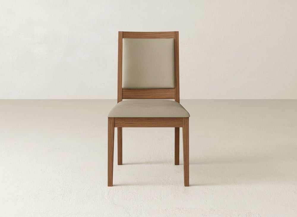 The James+James Gina Side Dining Chair showcases a maple wood frame with light beige upholstery on the seat and backrest, set against a neutral, light-colored wall and floor backdrop.