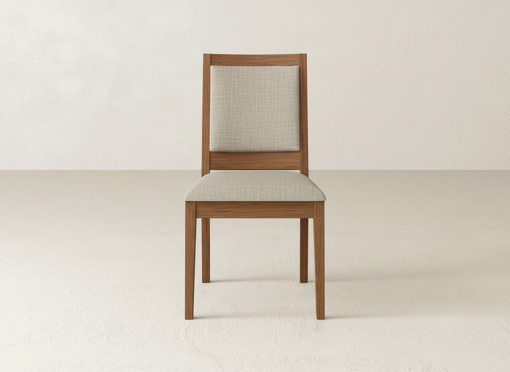 The James+James Gina Side Dining Chair, crafted from maple with light beige upholstery on the seat and backrest, sits on a plain light floor against an off-white wall.