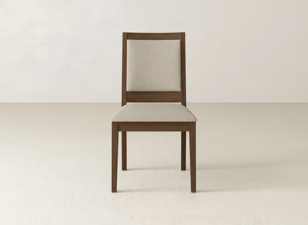 The Gina Side Dining Chair by James+James features a maple wood frame with a light beige upholstered seat and backrest, shown on a plain light floor against a neutral wall.