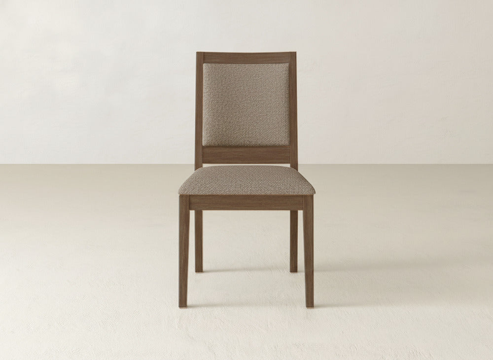 The Gina Side Dining Chair by James+James features a maple wood frame and padded seat and backrest in light beige fabric, shown on a light floor against an off-white wall.