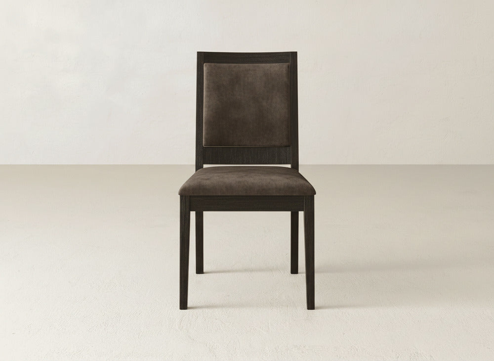 The Gina Side Dining Chair by James+James showcases dark maple wood and a cushioned brown fabric seat, set on a light floor with an off-white wall—an ideal modern dining chair for any space.