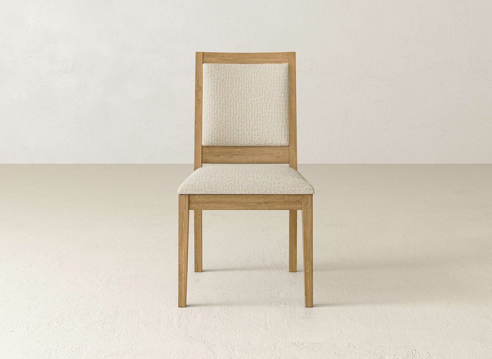 The Gina Side Dining Chair by James+James features clean, simple lines with a maple wood frame and light beige upholstered seat and backrest, set against a plain off-white background for a minimalist look.