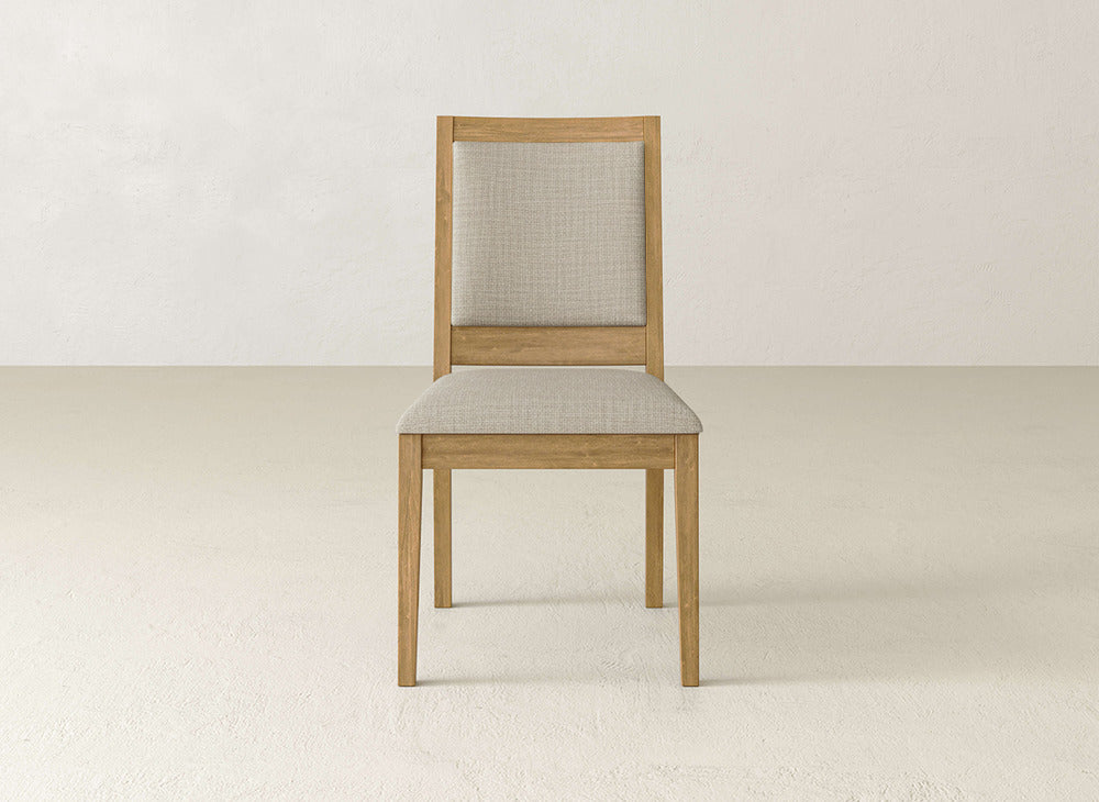 The Gina Side Dining Chair by James+James showcases a maple wood frame and light beige upholstered seat and backrest, set on a plain light floor with a neutral wall background.