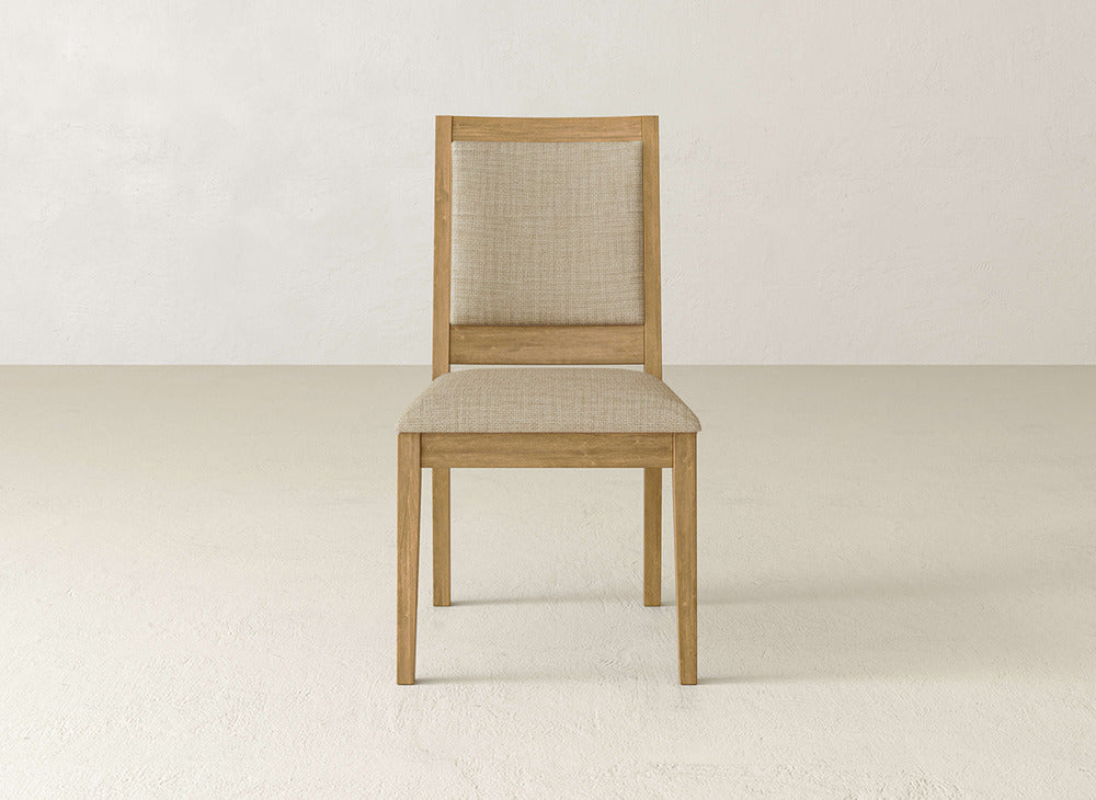 The Gina Side Dining Chair by James+James is a modern maple wood chair with light beige upholstery, shown on a plain, light floor against a white wall.