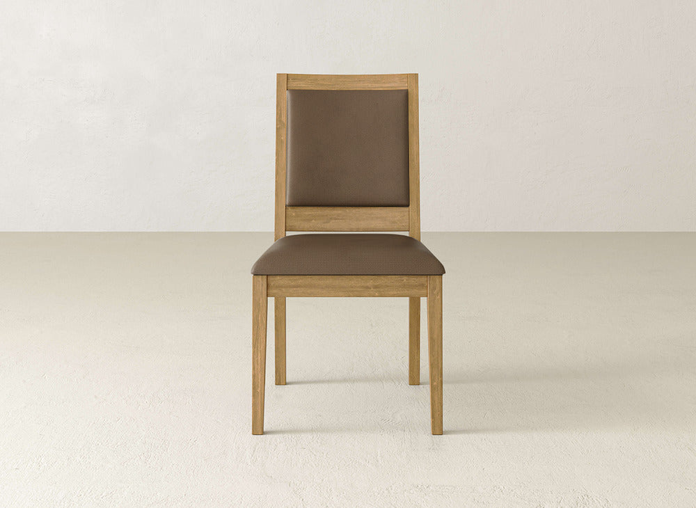 The James+James Gina Side Dining Chair, crafted from maple wood, features a light brown frame with a dark brown padded seat and backrest, shown on a light floor against an off-white wall.