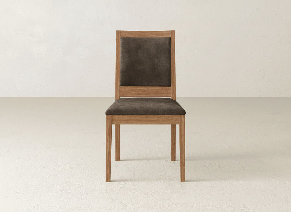 The James+James Gina Side Dining Chair, made from maple wood, features a dark brown cushioned seat and backrest. It is shown on a light floor against an off-white wall.