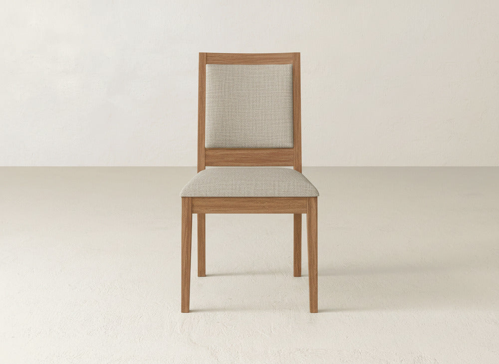 The Gina Side Dining Chair by James+James features a light beige cushioned seat and backrest on maple wood, sitting elegantly against a light background—ideal for modern dining spaces.