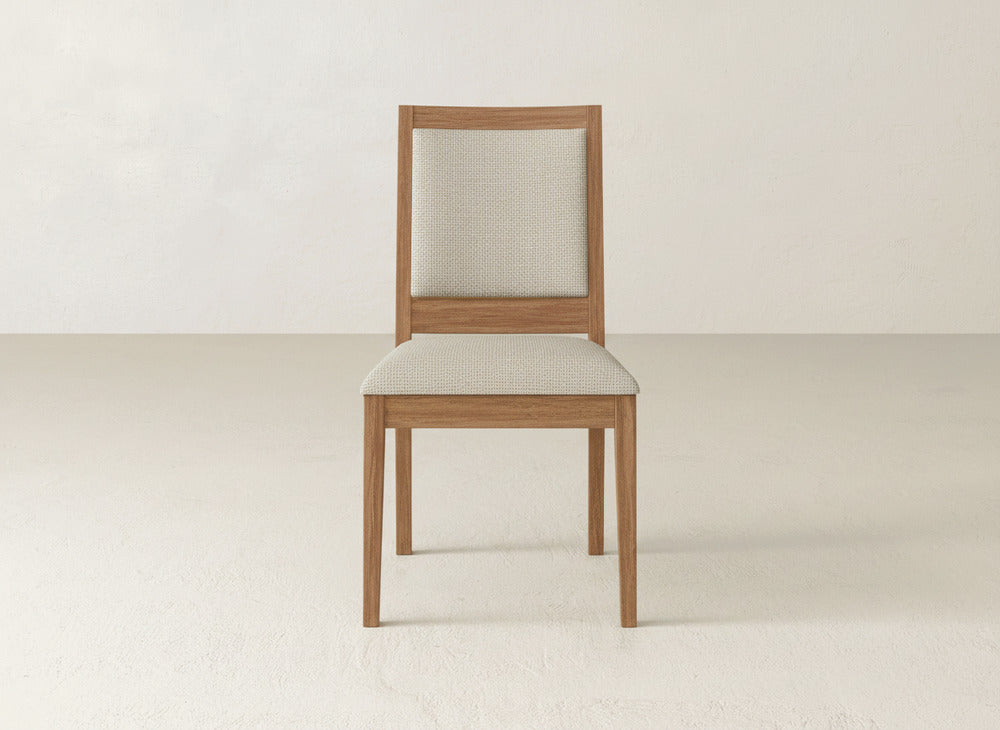 The James+James Gina Side Dining Chair, made from maple wood, features a light beige cushioned seat and backrest. Set against an off-white background, it highlights a simple, modern design.