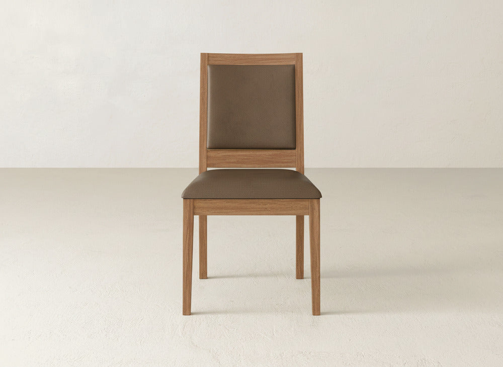 A James+James Gina Side Dining Chair with maple wood frame and brown cushioned seat and backrest is placed against a plain, light-colored wall and floor.