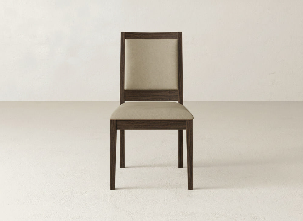 The James+James Gina Side Dining Chair features a beige cushioned seat and backrest crafted from maple wood, shown on a light floor against an off-white wall.