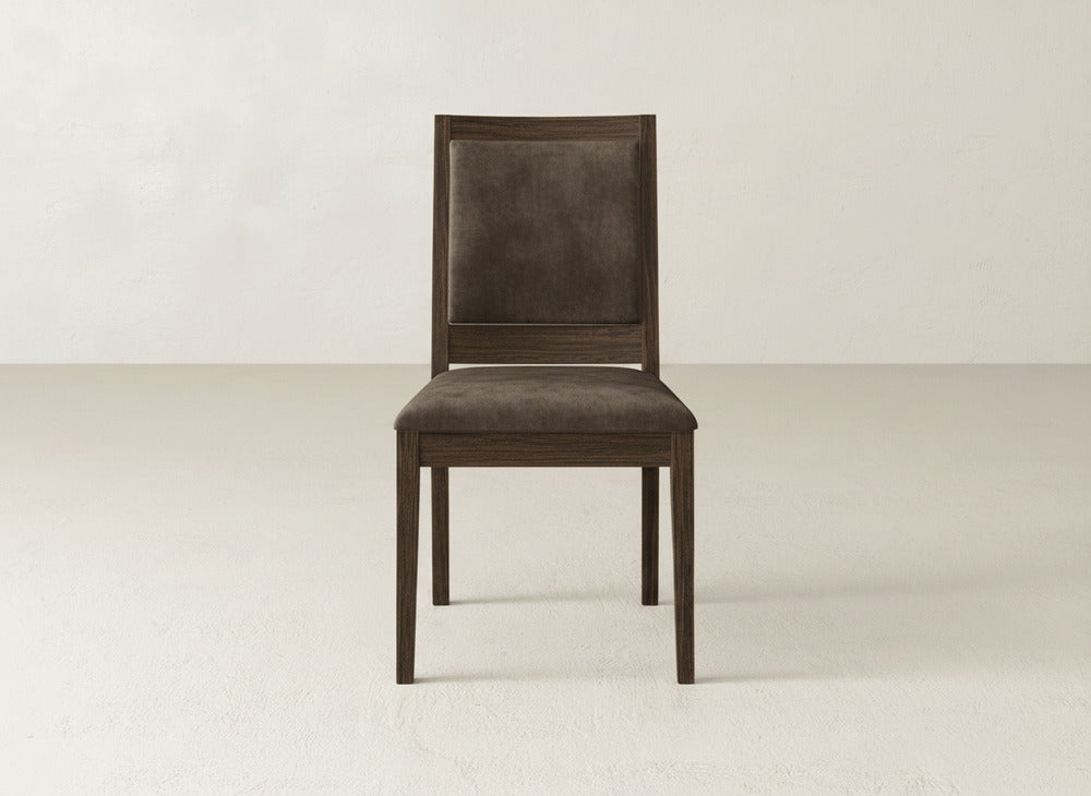 The Gina Side Dining Chair by James+James showcases dark maple wood with a cushioned seat and backrest in dark fabric, set on a light floor against an off-white wall.