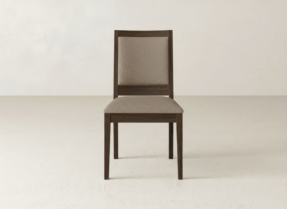 The Gina Side Dining Chair by James+James is made from maple wood and features a padded, light brown upholstered seat and backrest, shown facing forward against a plain, light-colored wall and floor.