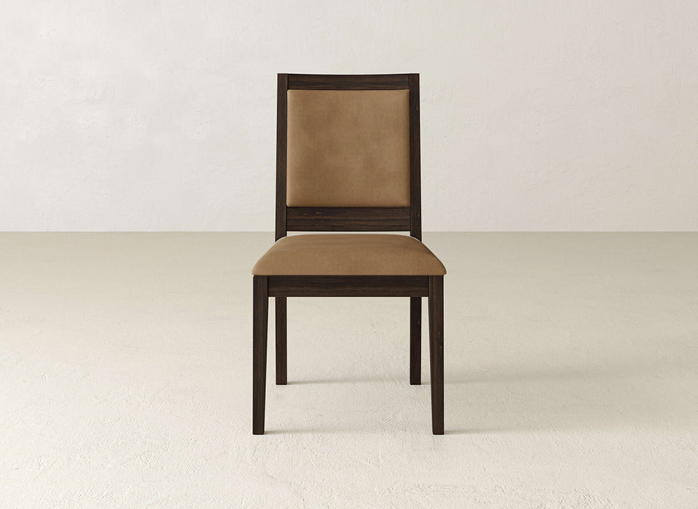 The James+James Gina Side Dining Chair, featuring a dark brown frame and light brown padded seat and backrest in maple wood, is centered in a minimalist room, highlighting its modern elegance.