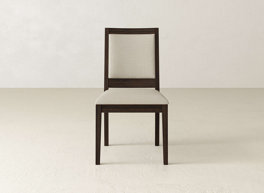 The James+James Gina Side Dining Chair showcases a dark maple wood frame with a light beige upholstered seat and backrest, set on a plain, light-colored floor against a neutral wall background.