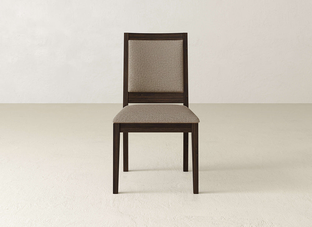 The James+James Gina Side Dining Chair showcases maple wood, a cushioned seat and backrest upholstered in light beige fabric, displayed against an off-white wall and floor.