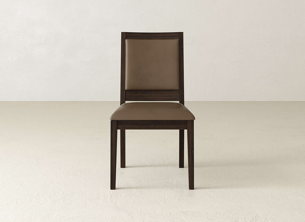 The Gina Side Dining Chair by James+James features maple wood with a brown padded seat and backrest. Styled against an off-white wall and light floor, it offers a simple, modern look for any dining space.