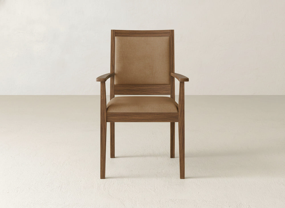 The James+James Gina Arm Dining Chair features straight armrests and legs with a brown cushioned seat and backrest, set against a plain light-colored wall and floor.