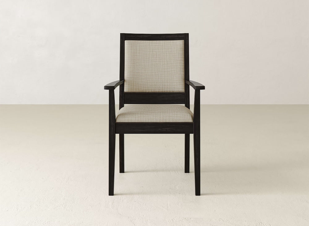 The James+James Gina Arm Dining Chair features a dark maple wood frame, light upholstered seat and backrest, and straight armrests, presented against a simple light backdrop.
