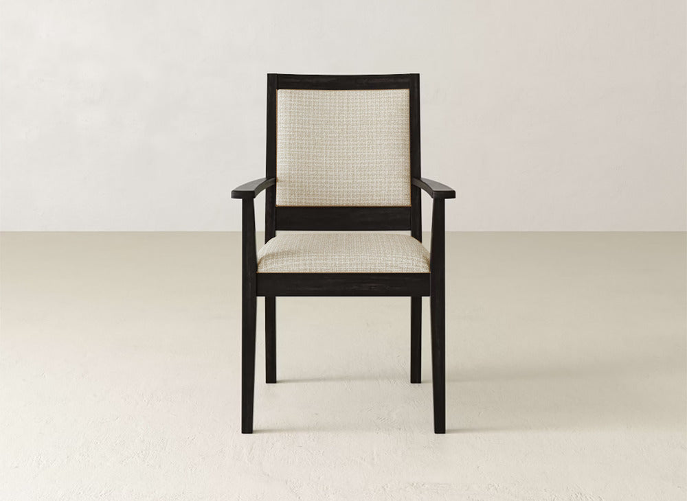 The James+James Gina Arm Dining Chair is a modern piece with a dark maple frame and light, textured fabric on the seat and back, shown on a light floor against an off-white wall.