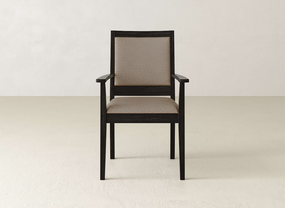 The James+James Gina Arm Dining Chair is a contemporary piece with a dark maple frame and beige upholstered seat and backrest, shown against a plain, light-colored wall and floor.