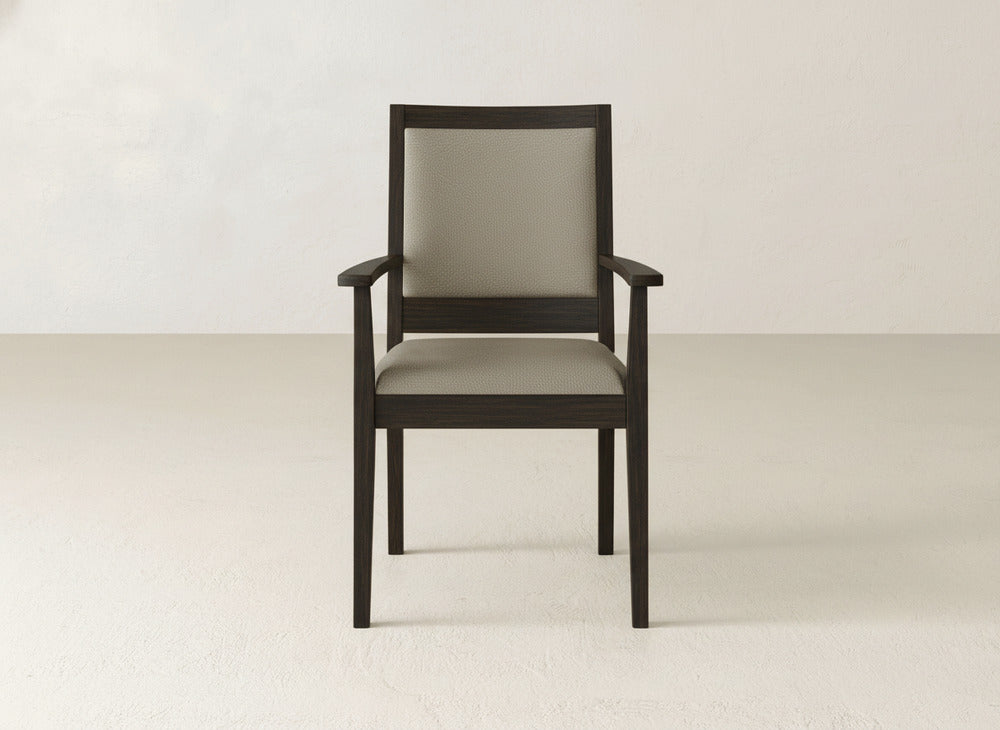 The Gina Arm Dining Chair by James+James is a contemporary piece with a modern maple wood frame and light beige upholstered seat and back, pictured on a light floor against an off-white wall.