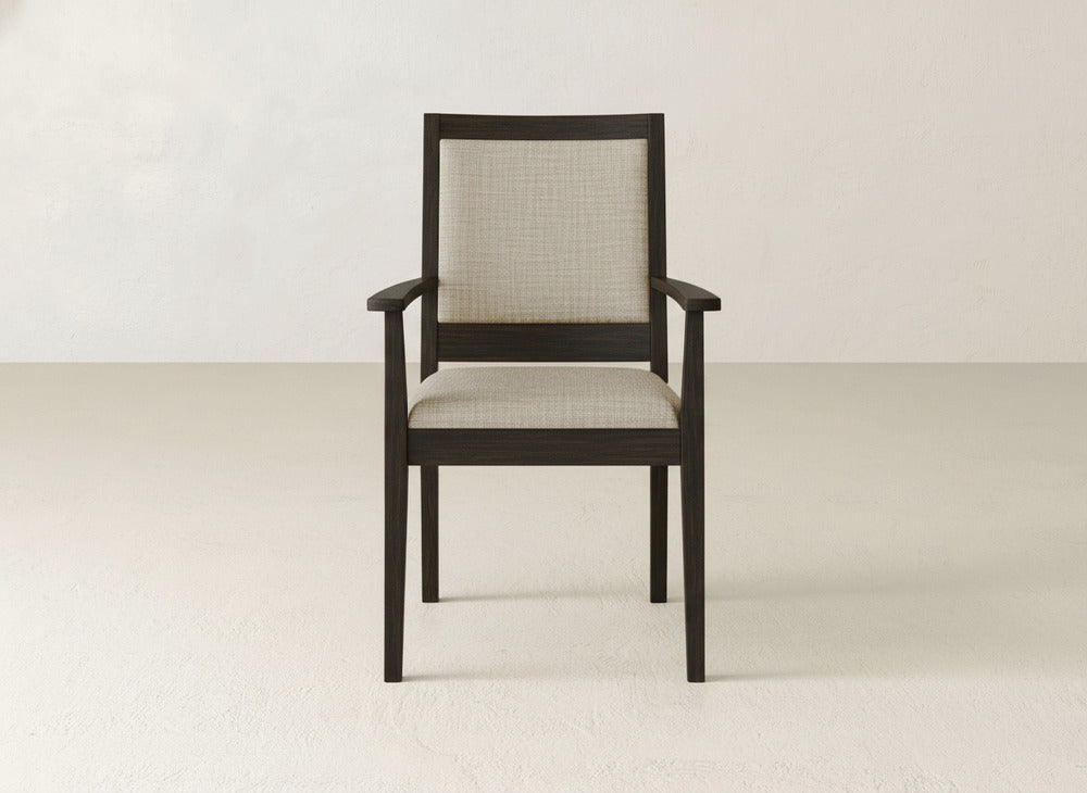 The Gina Arm Dining Chair by James+James features a dark maple frame, beige upholstered seat and backrest, and straight armrests, set against a plain light background.