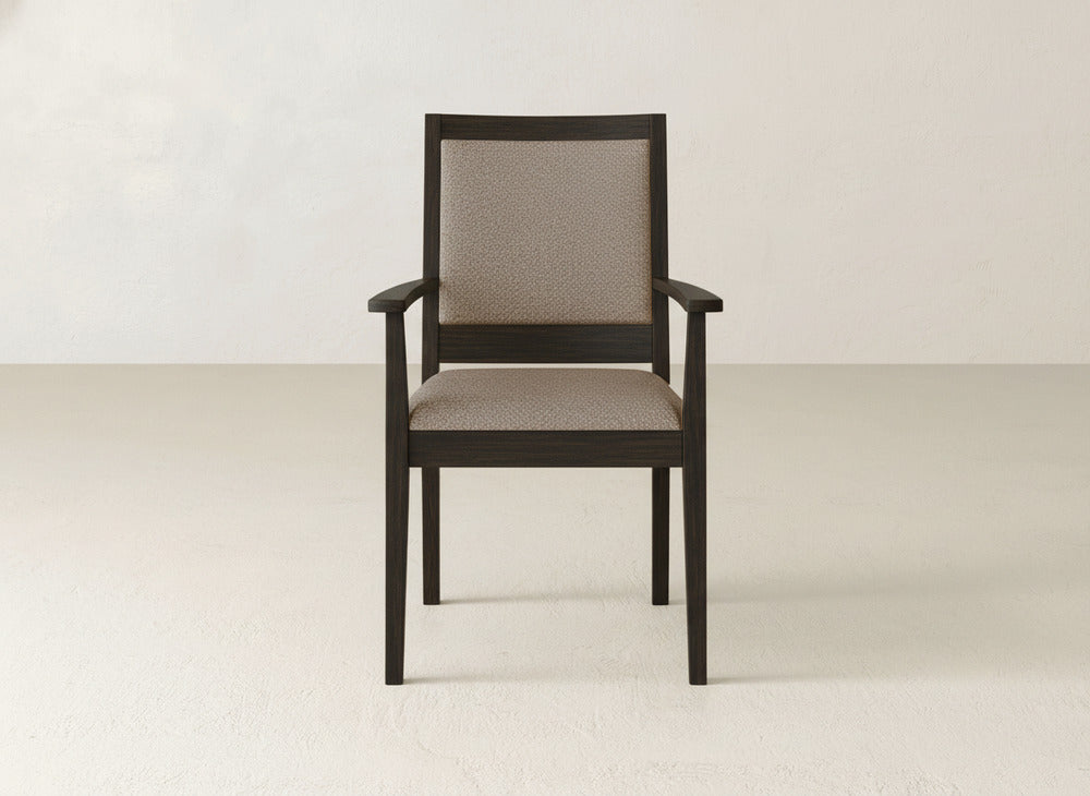 The Gina Arm Dining Chair by James+James features a dark brown maple wood frame and a light beige upholstered seat and backrest, set on a plain light-colored floor with a neutral wall background.