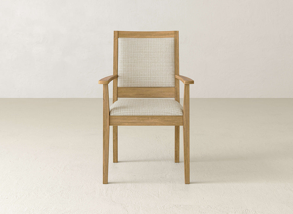 The Gina Arm Dining Chair by James+James is crafted from maple wood with a light beige upholstered seat and backrest. Its simple, modern design and clean lines make it an ideal choice for contemporary dining spaces.
