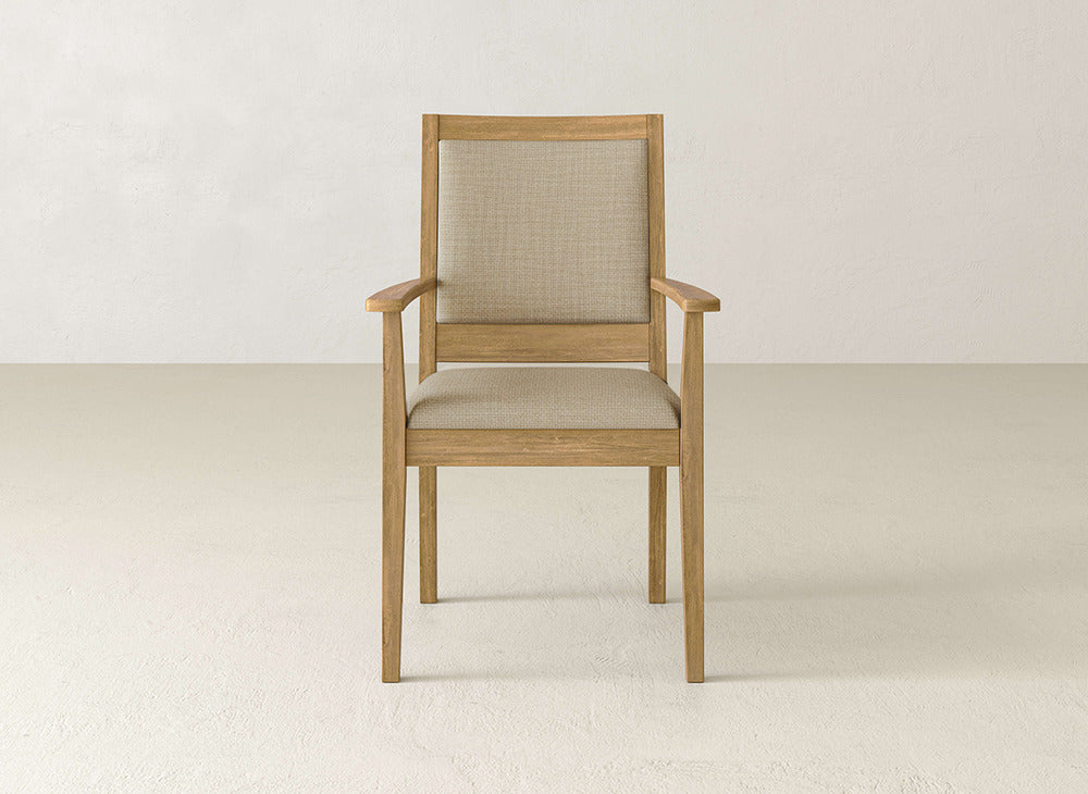 The Gina Arm Dining Chair by James+James is a modern maple wood chair with beige upholstery on the seat and backrest, shown on a light floor against an off-white wall.