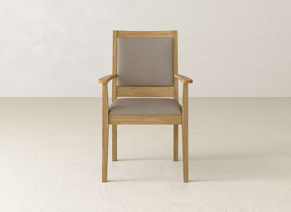 The Gina Arm Dining Chair by James+James is a contemporary maple chair with light brown upholstered seat and backrest, displayed on a beige floor against an off-white wall.