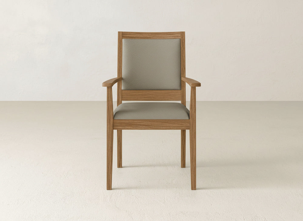 The Gina Arm Dining Chair by James+James is a modern dining chair with armrests, featuring a light brown maple wood frame and light gray cushioned seat and backrest, set against a plain, light-colored background.