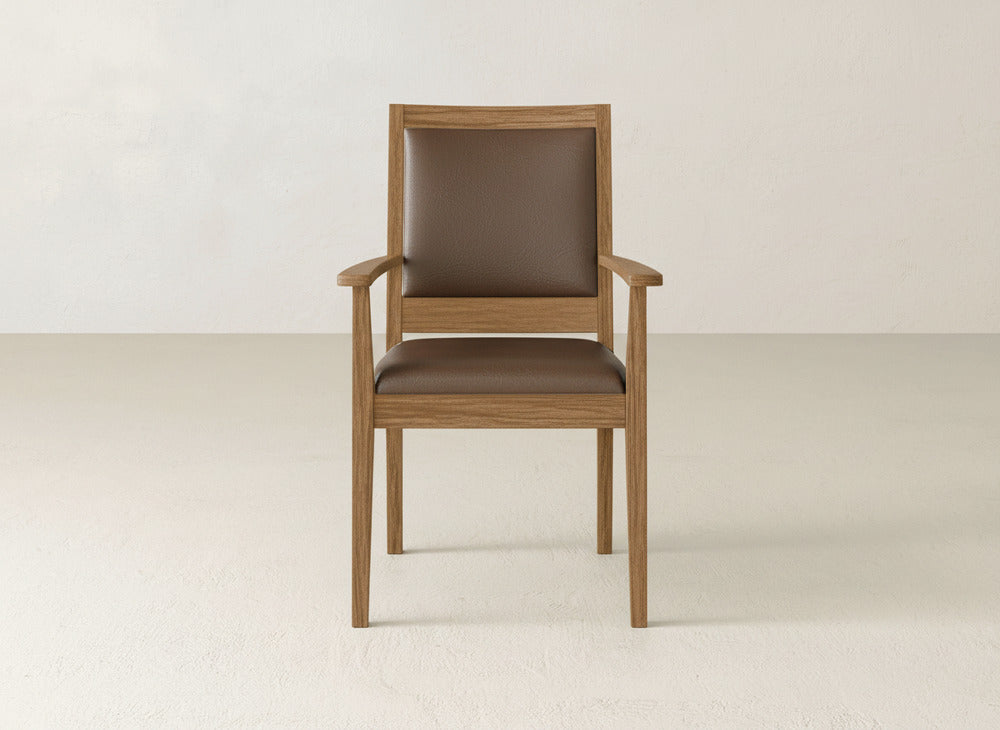 The Gina Arm Dining Chair by James+James is a modern maple wood chair with a brown padded seat and backrest, shown against a light-colored wall and floor.