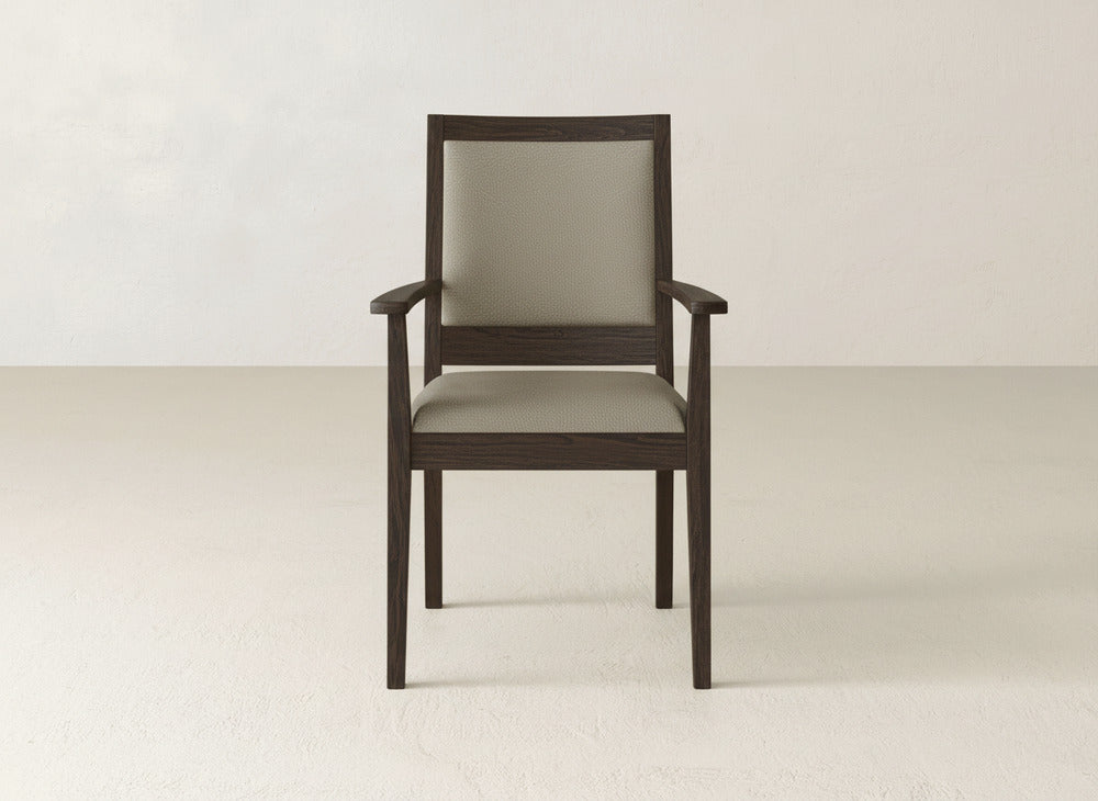 The Gina Arm Dining Chair by James+James showcases a dark maple wood frame and light beige upholstery, offering refined, contemporary style. It looks elegant on a light floor with a plain off-white wall backdrop.