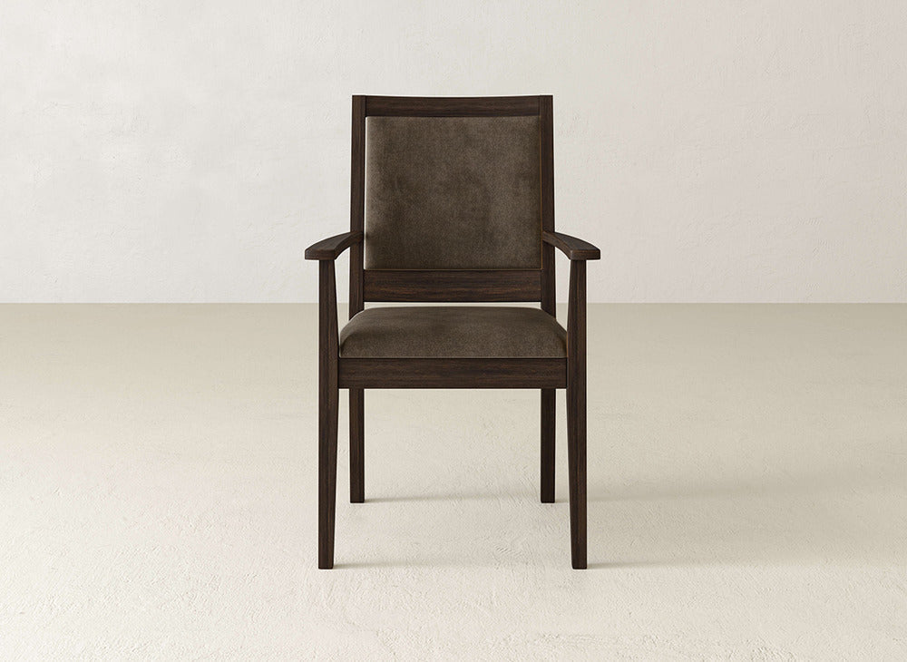 The Gina Arm Dining Chair by James+James is a modern maple wood chair with a brown upholstered seat and backrest, shown against a light-colored wall and floor.