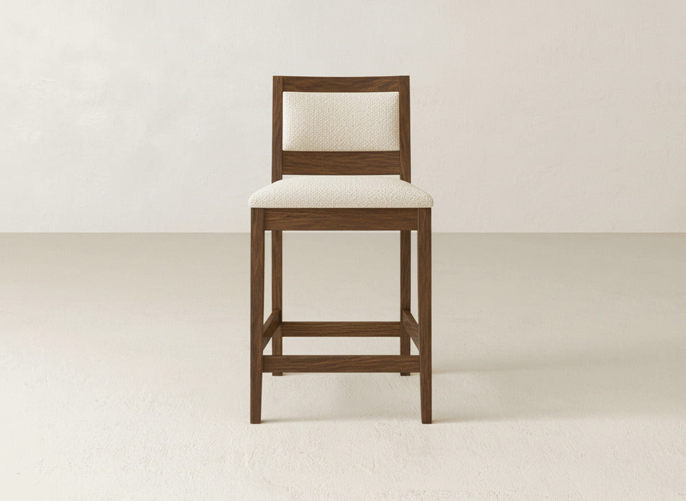 The Gina Side Stool by James & James showcases modern design with a maple wood frame and beige cushioned seat and backrest, styled against a light background.