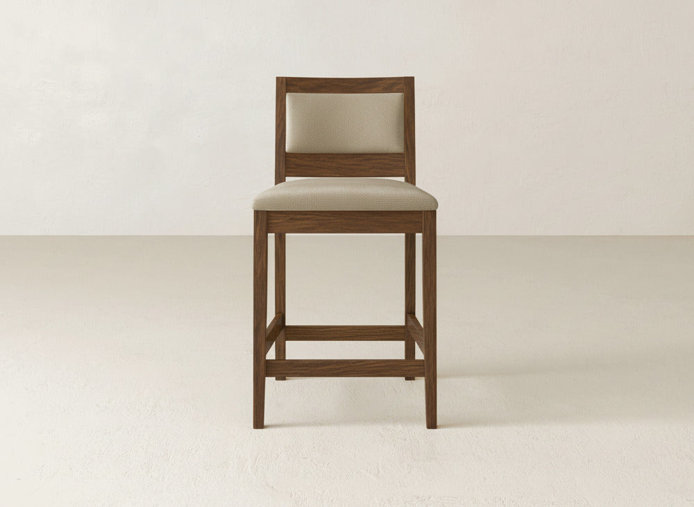 The Gina Side Stool by James & James showcases a modern maple wood frame with a beige cushioned seat and backrest, placed on a light floor against an off-white wall.