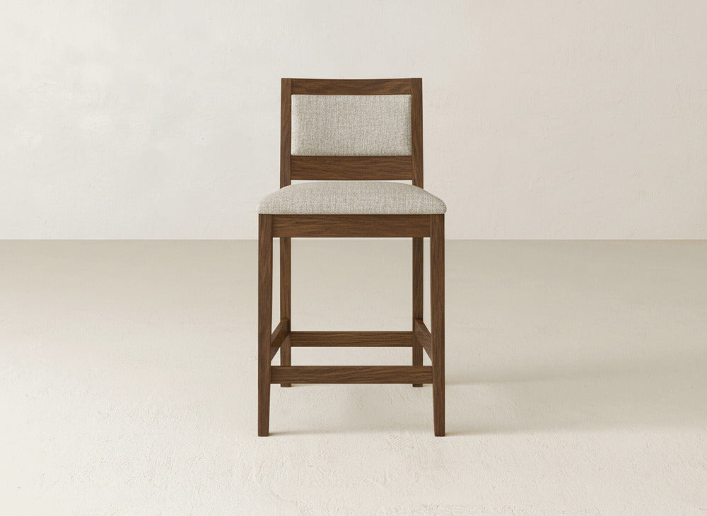 The Gina Side Stool by James & James features a beige upholstered seat and backrest crafted from elegant maple wood, presented against a plain, light-colored background.