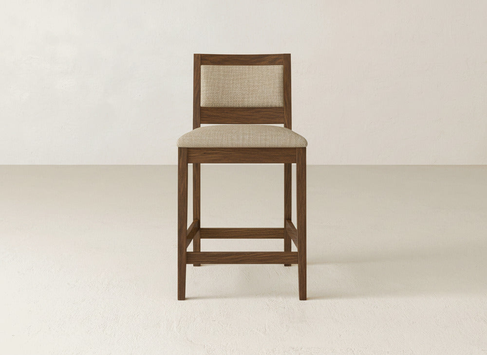 The Gina Side Stool by James & James features a modern design with a beige upholstered seat and backrest, crafted from maple wood, shown against a plain light background.