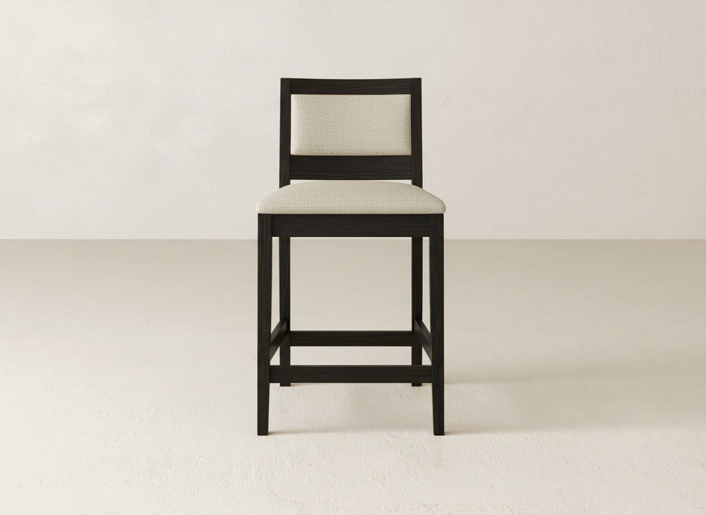 The Gina Side Stool by James & James showcases a modern design with a dark maple frame and light upholstery, perfectly complementing minimalist spaces with plain white walls and light floors.