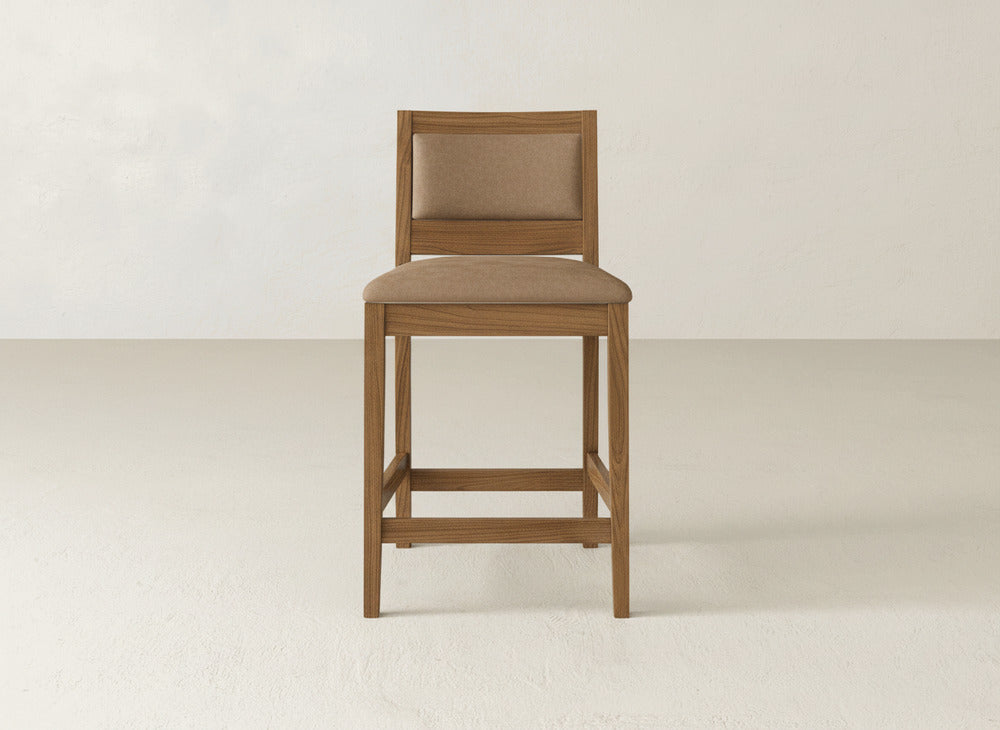 The Gina Side Stool by James & James features a modern design with a cushioned seat and backrest in light brown fabric, set on maple wood. This stylish bar stool stands out beautifully against a plain, light-colored background.