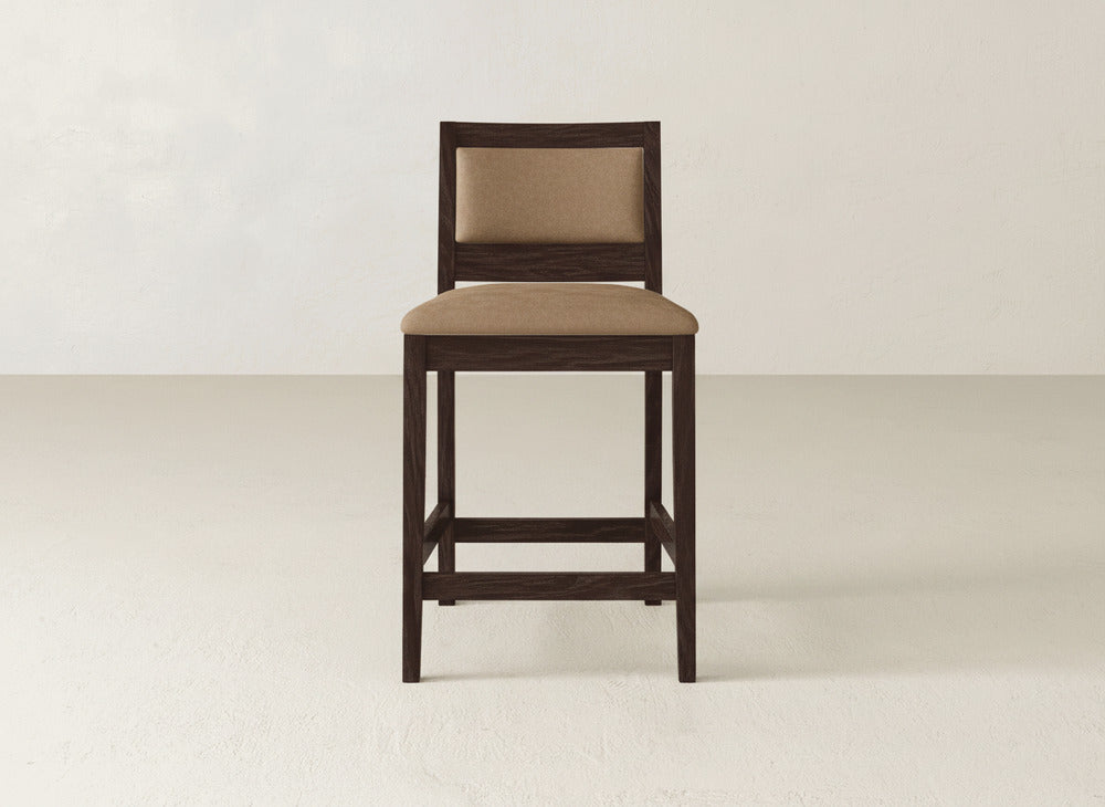The James & James Gina Side Stool showcases a modern design with a dark brown maple frame and light brown cushioned seat and backrest, set on a plain, light floor against a neutral wall.