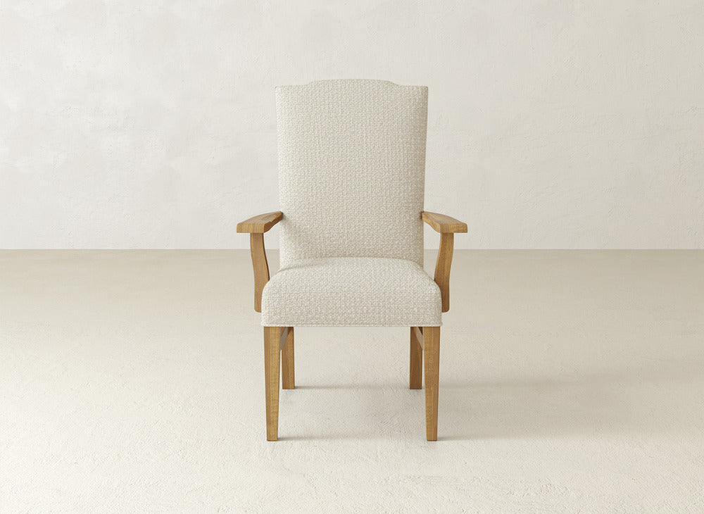 The James+James Hadley Arm Dining Chair features a wooden frame, light beige upholstered seat, high back, and arms, displayed against a plain light background.