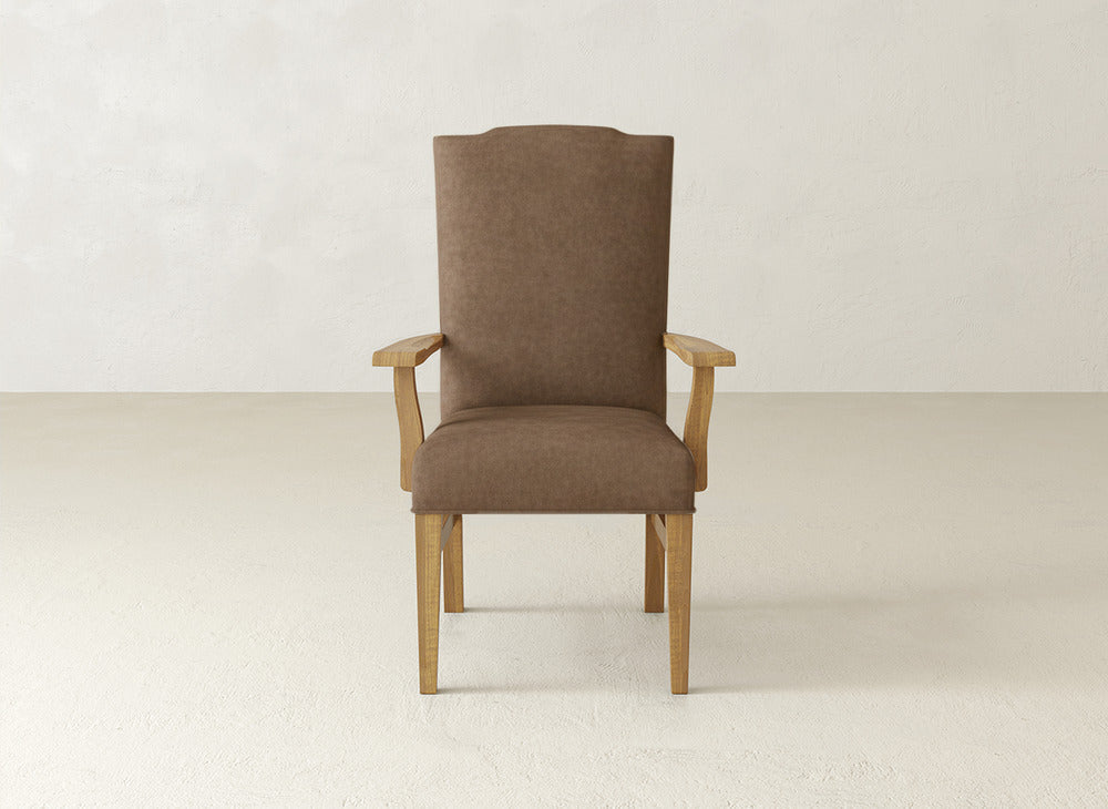 The Hadley Arm Dining Chair by James+James features a stylish, comfortable design with a high backrest and brown upholstered seat and back, shown against a plain light-colored background.