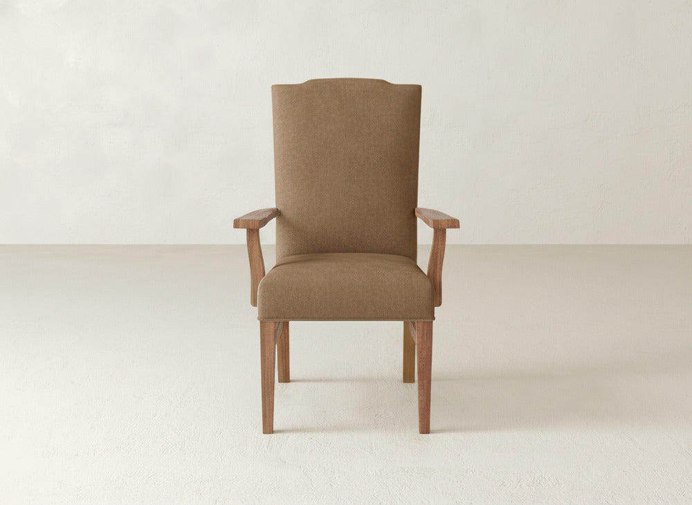 The Hadley Arm Dining Chair by James+James is a brown upholstered chair featuring wooden legs and armrests, showcased against a plain, light-colored background.